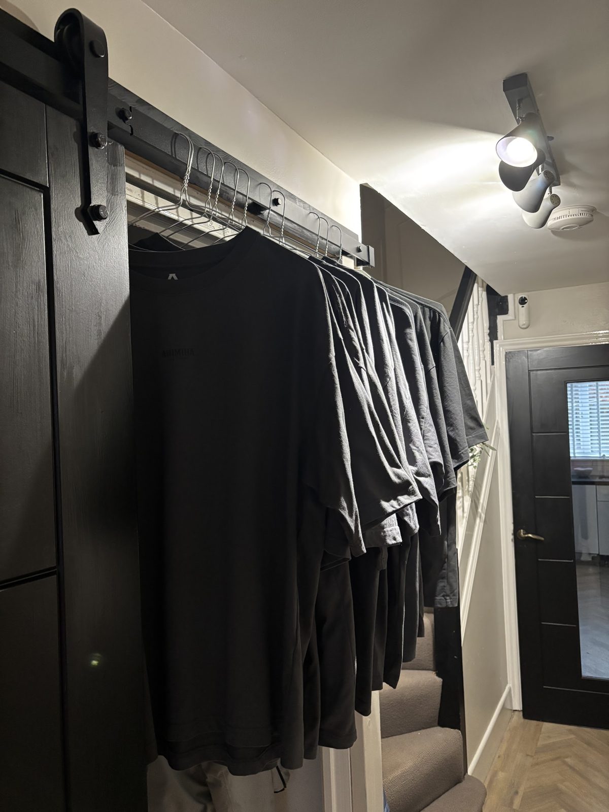 A row of pressed black T-shirts on hangers