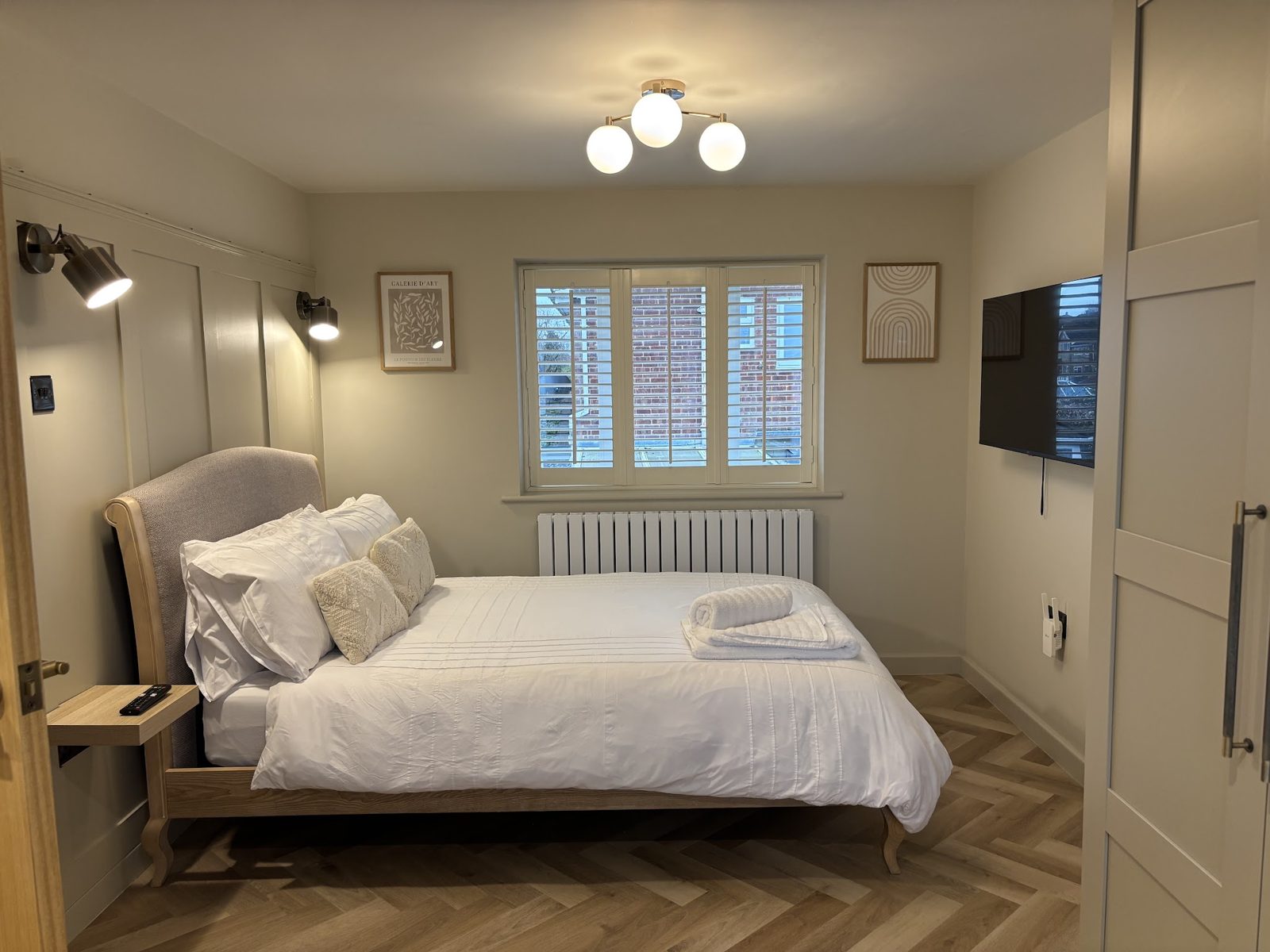 A holiday let bedroom with fresh white bedding and rolled towels at the foot of the bed