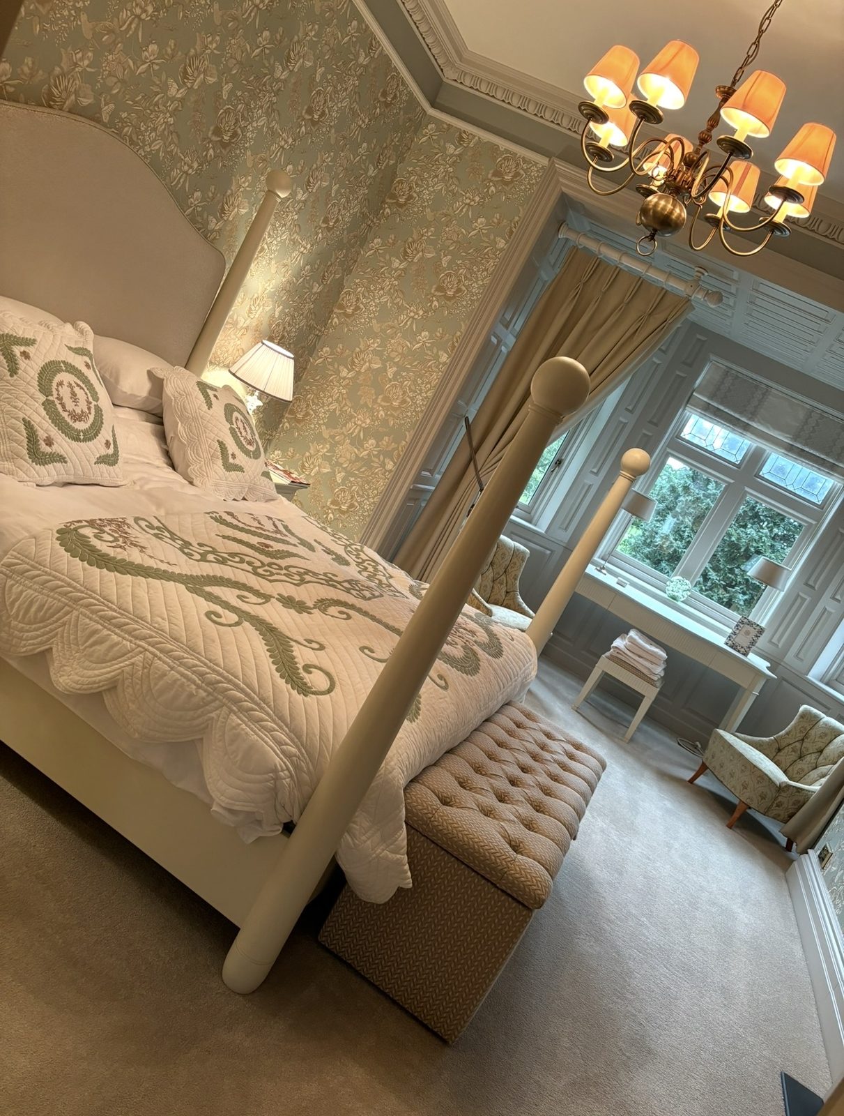 A four-poster bed made up with a crisp quilted bedspread in an elegant bedroom