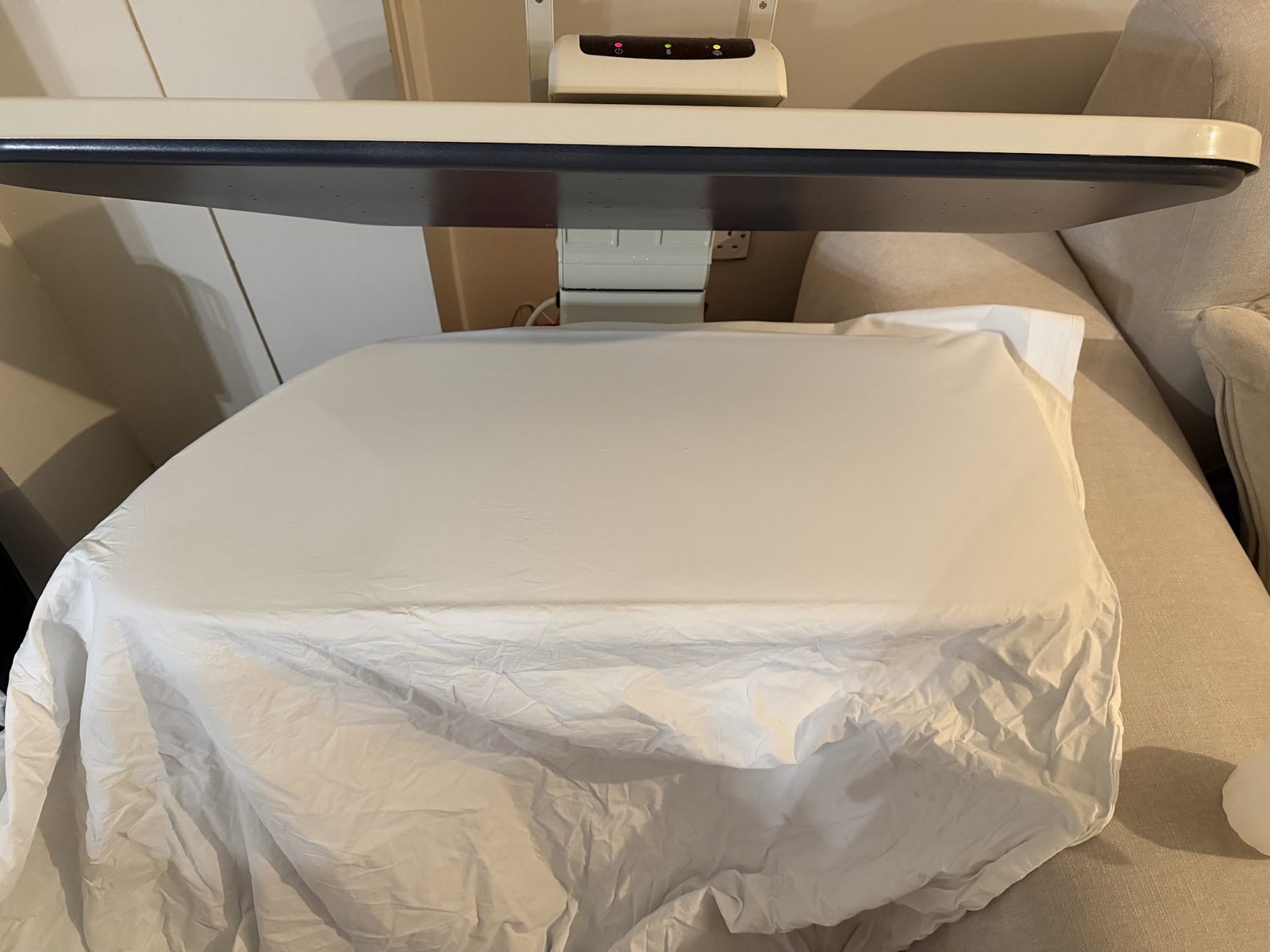 A white sheet under a steam ironing press