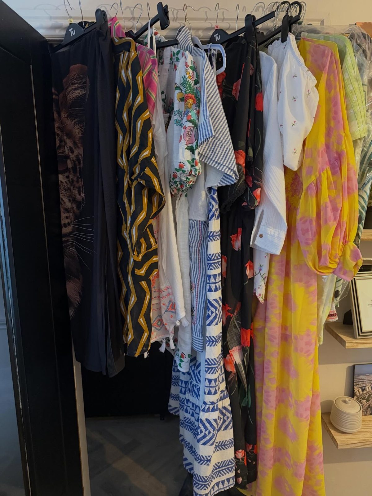 A rail of colourful dresses and shirts, pressed and on hangers